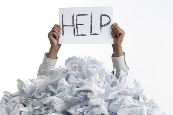 Business Person Buried Under Crumpled Paper Holding Help Sign