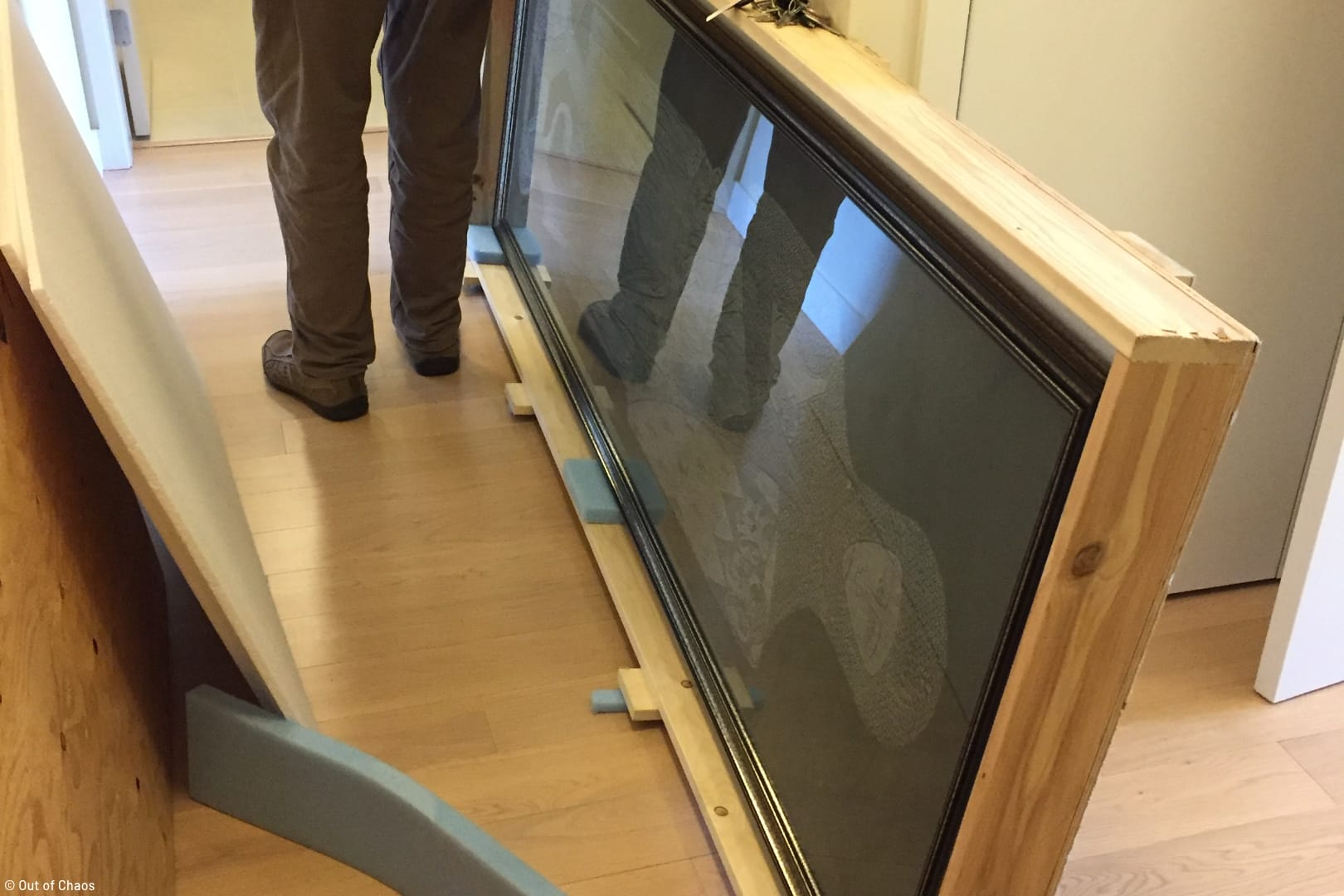 view of wood crate on the floor containing a large framed painting
