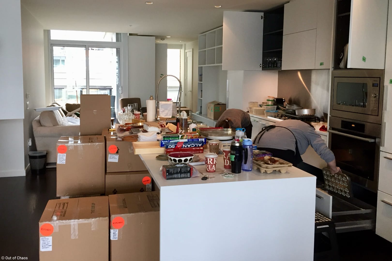 the Out of Chaos team packing kitchen items in a kitchen surrounded by packing materials and boxes