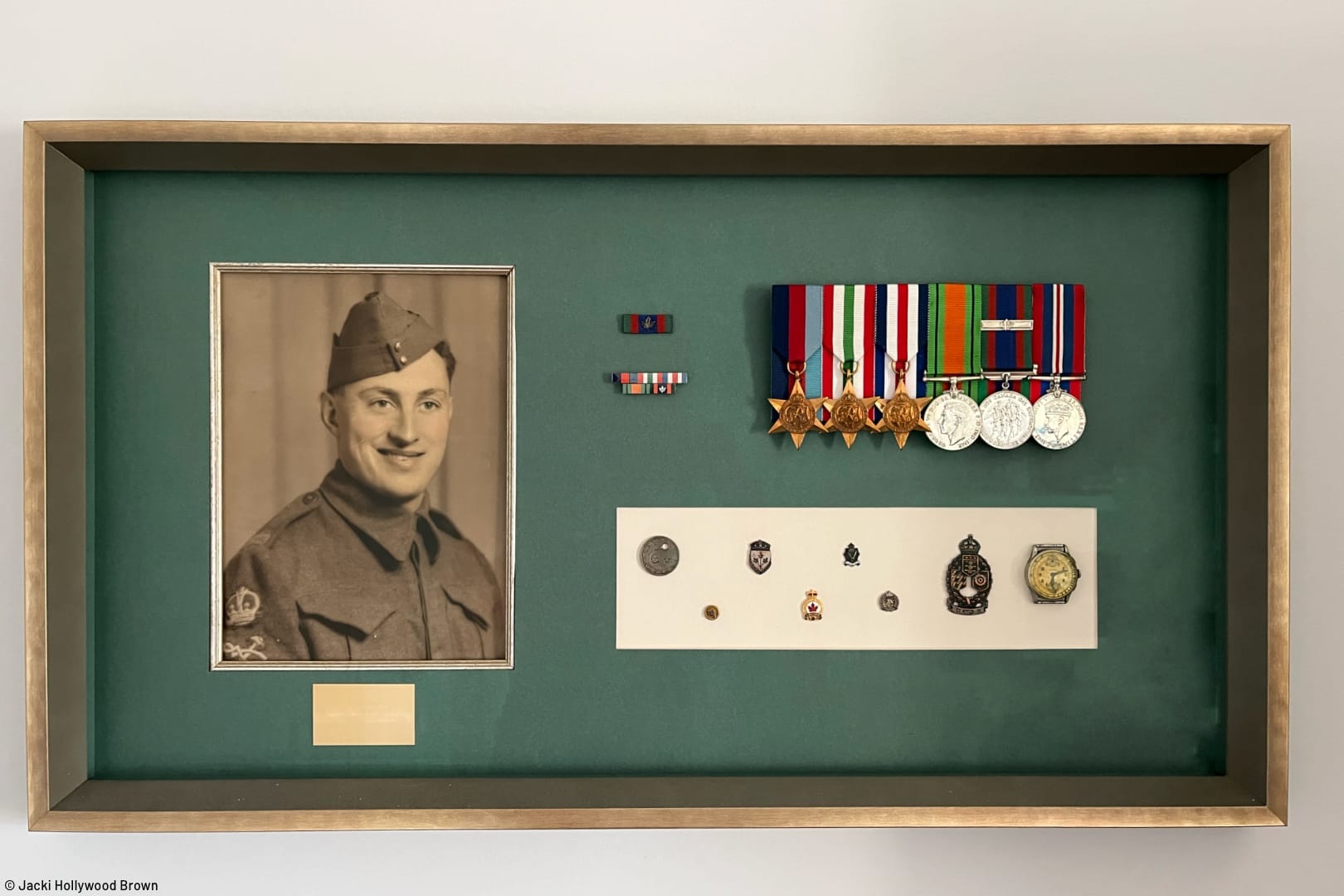 shadow box containing image of World War 2 soldier in uniform with military medals, ribbons, and assorted badges