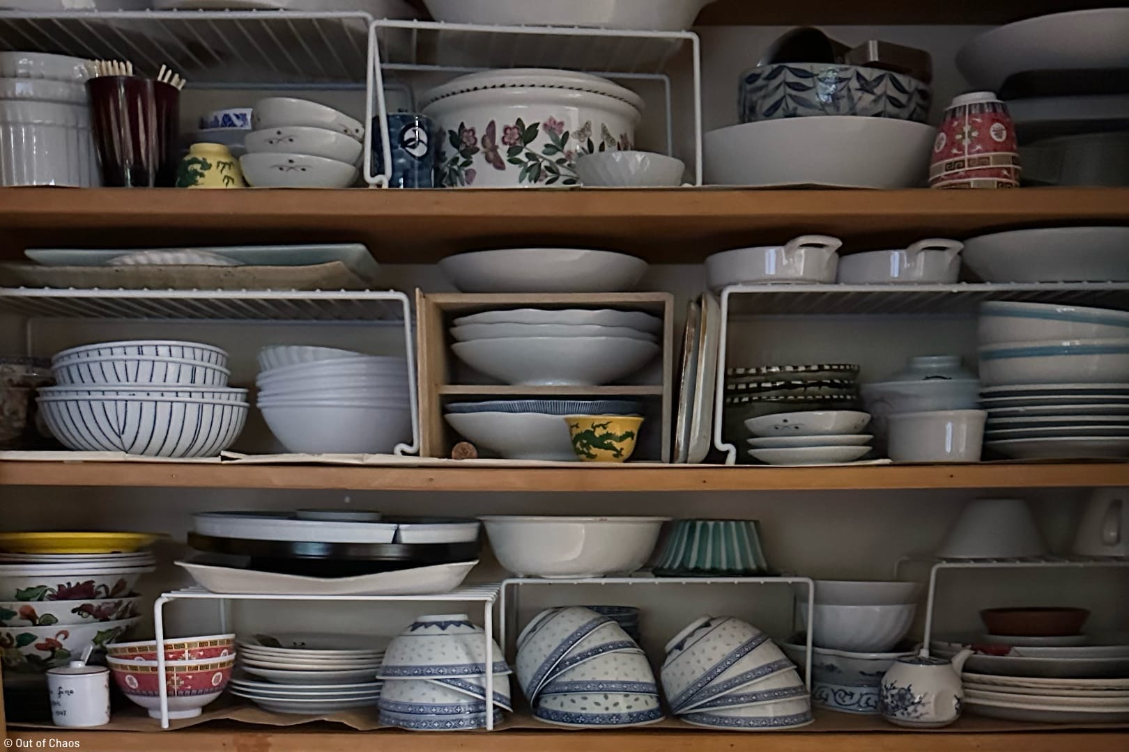 cupboard full of dishes stacked high on every shelf