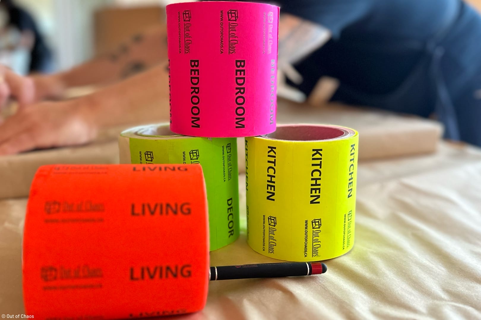 brightly coloured stickers for moving boxes in the foreground and a person packing household goods in the background representing a stress-free move